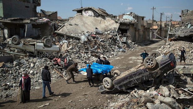 Residents carry the body of several people killed during fights between Iraq security forces and IS on the western side of Mosul on Friday.