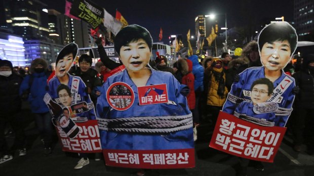 Protesters hold cutouts of President Park Geun-hye as they march during a candlelight vigil calling for her to step down on January 14.