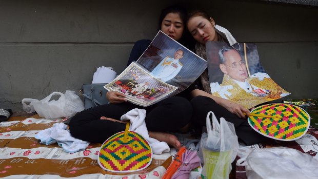 Dressed in black for mourning, two women sleep on the footpath outside Siriraj Hospital in Bangkok following the death of Thai King Bhumibol Adulyadej.