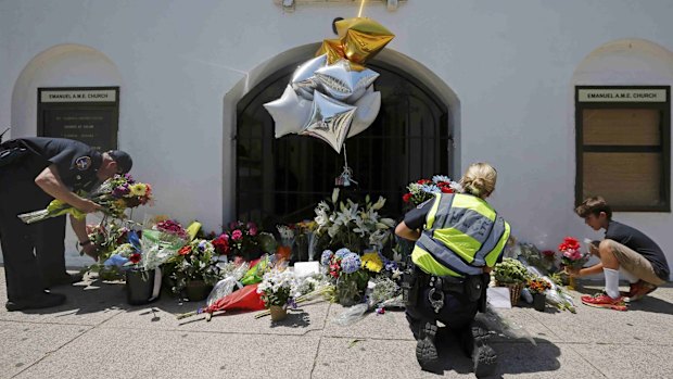 Liam Eller, 9, helps police officers move flowers left outside Emanuel African Methodist Episcopal Church.