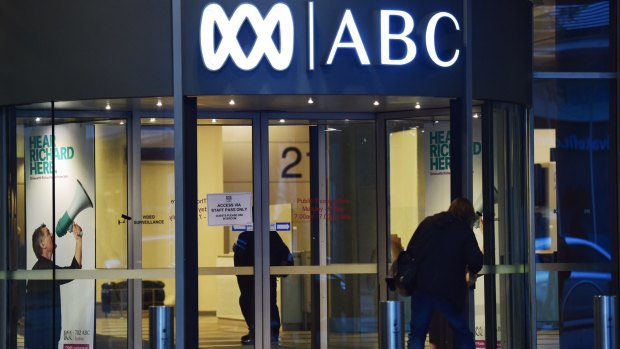 An ABC worker swipes a security card to enter the Ultimo Centre on Friday morning amid a security lockdown, as a security officer guards the door.