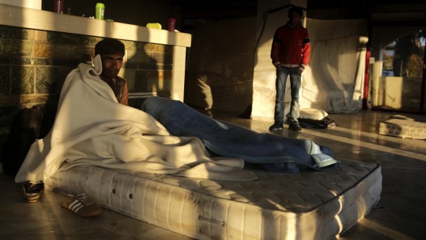 A man from Pakistan sits on a mattress at an abandoned hotel where immigrants have been given shelter on the Greek island of Kos.