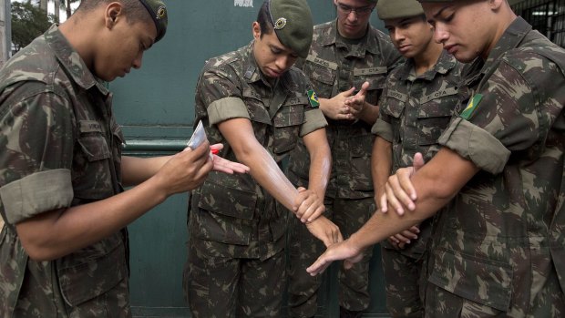 Army soldiers apply insect repellent as they prepare for a clean-up operation against the Aedes aegypti mosquito in Sao Paulo. 