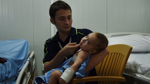 Hisham Haitham comforts his wounded baby cousin Qasid Radhwan at the Athba Field Hospital. Qasid was hit by shrapnel, causing a part of his lung to collapse.