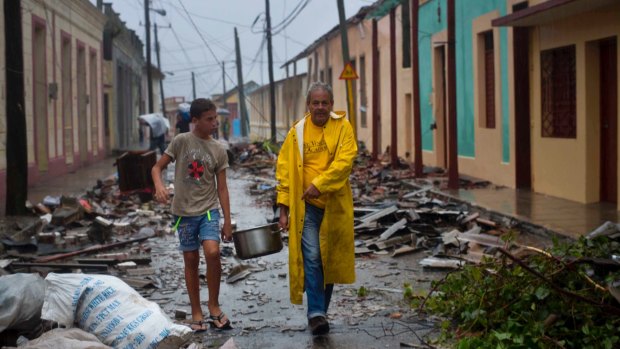 Residents carry food down a street strewn with rubble caused by Hurricane Matthew in Baracoa, Cuba.