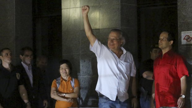 Jose Dirceu gestures to supporters as he turns himself in to federal police after an arrest warrant was issued for him to begin a jail sentence for corruption last November.