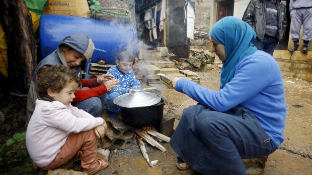 A Syrian refugee with her children prepares food near her tent in a camp for Syrians in the Chouf mountain town of Ketermaya, Lebanon. 