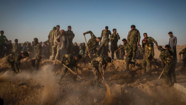 Syrian Democratic Forces militiamen bury their comrade Omar al-Abed, who they say  died after grabbing an Islamic State suicide bomber to shield his comrades.