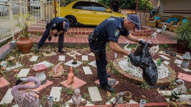 Police search a neighbour's garden and garbage bins after Kelly Ventigadoo was fatally stabbed. 