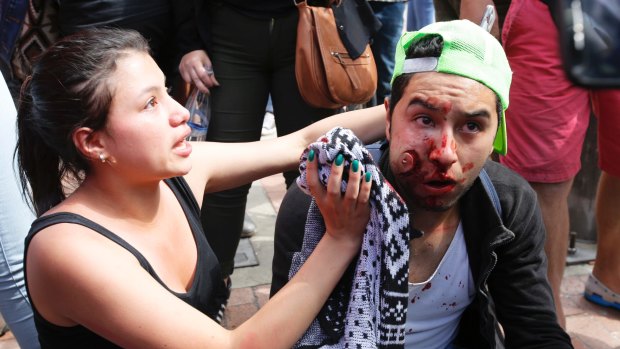 A woman aids a man injured during clashes between animal rights activists and police ahead of the January bullfight.