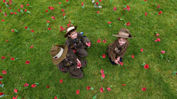 Isabella Doughty, Riley Gilbert and Grace Doughty plant poppies at the Shrine in honour of their grandfathers and great-great grandfather who fought in both world wars.