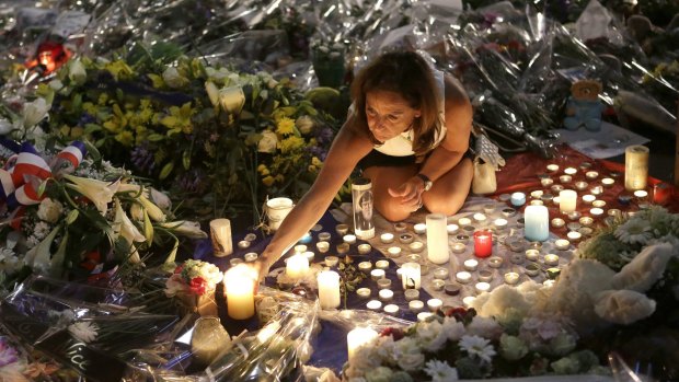 A woman lights candles at a memorial for the victims of the Bastille Day attack in Nice.