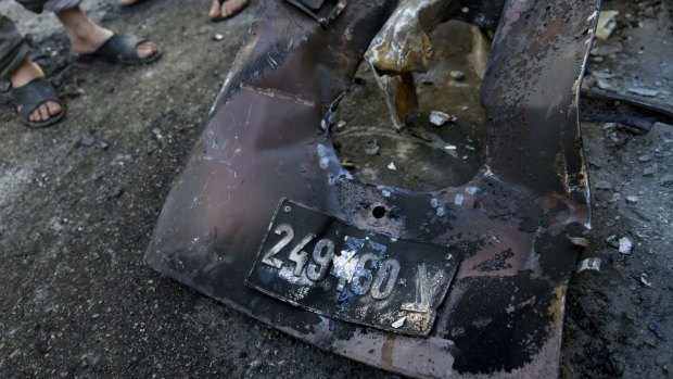 Palestinians inspect abandoned parts with the registration plate of an Israeli army vehicle that was burnt during an Israeli army raid in the West Bank refugee camp of Qalandia.