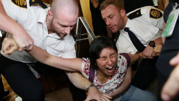 Woman screams as she's removed from Parliament House in Canberra on Wednesday.
