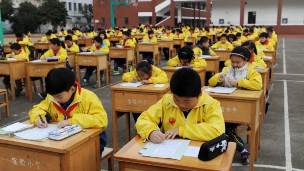Chinese primary school students compete in calligraphy on the playground in Dongyang of Jinhua City. 