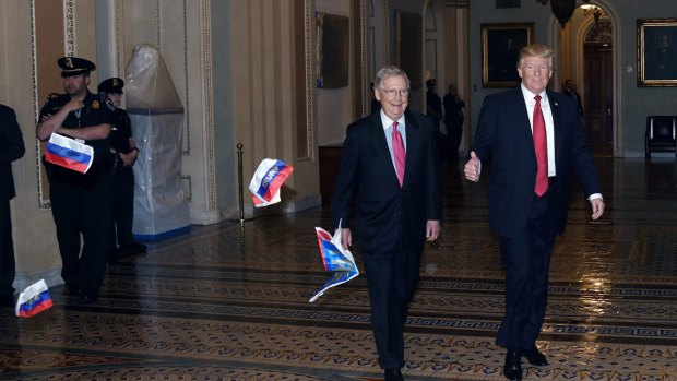 Russian flags displaying the word Trump are thrown by a protester, not pictured, as US President Donald Trump, right, and Senate Majority Leader Mitch McConnell, walk to a policy luncheon.