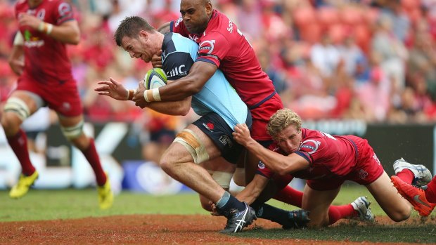 Surrounded: Jed Holloway of the Waratahs is tackled during the round five match against the Reds at Suncorp Stadium.