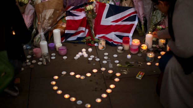 A British flag is seen next to flowers after a vigil in Albert Square, Manchester.