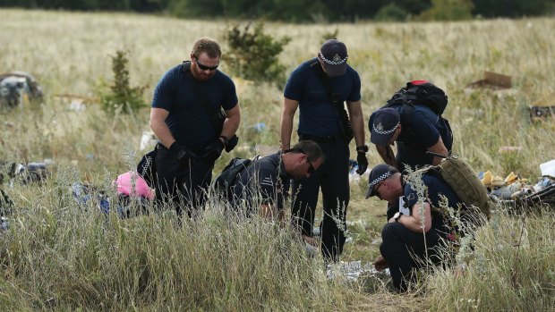 Australian Federal Police officers and their Dutch counterparts collect human remains from the MH17 crash site in the fields outside the village of Grabovka in eastern Ukraine in August of last year. 