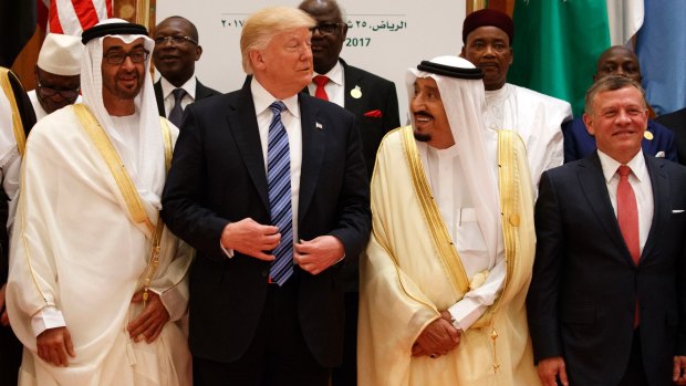 President Donald Trump talks with Saudi King Salman as they pose for photos with leaders at the Arab Islamic American Summit.