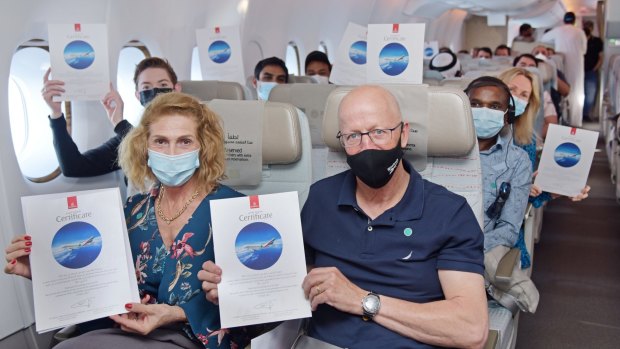 Passengers display their commemorative certificates on board the Emirates flight.