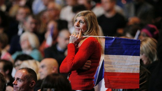 A woman holds a French national flag during a presidential campaign rally in Paris on Monday.