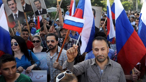 Syrians holding photos of President Bashar al-Assad and Russian flags, during a rally outside the Russian embassy that was hit by two shells fired by insurgents.
