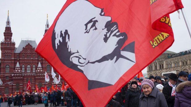 Communist party supporters with red flags and a flag with a portrait of Soviet Founder Vladimir Lenin.