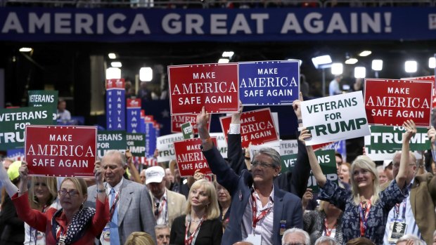 Delegates hold up signs and cheer during first day of the Republican National Convention in Cleveland.