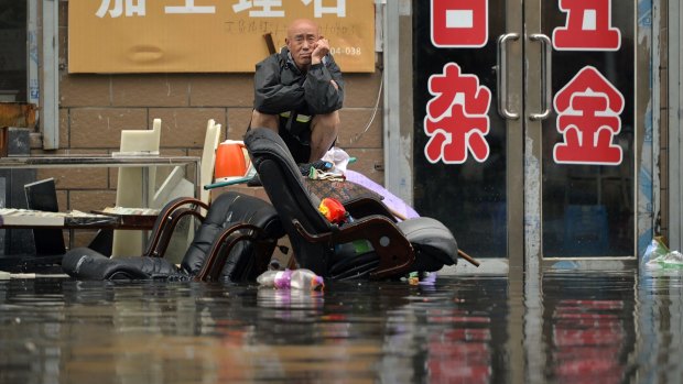 A man sits outside of a flooded shop in Shenyang in north-eastern China's Liaoning Province.  