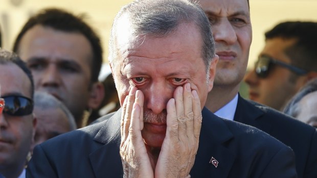 Turkish President Recep Tayyip Erdogan right, wipes his tears during the funeral of Mustafa Cambaz, Erol and Abdullah Olcak, killed on Friday while protesting the attempted coup.