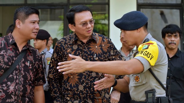 Jakarta governor Basuki Tjahaja Purnama, popularly known as Ahok, centre, listens to a police officer explain the plan for leaving North Jakarta District Court.