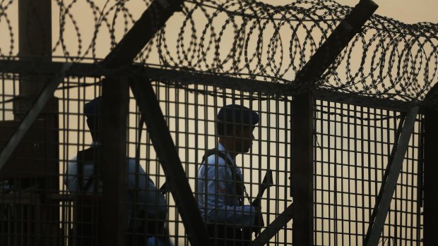 Indonesian police and security guard the fence of Ngurah Rai international airport during the transfer of Bali Nine duo Myuran Sukumaran and Andrew Chan. 