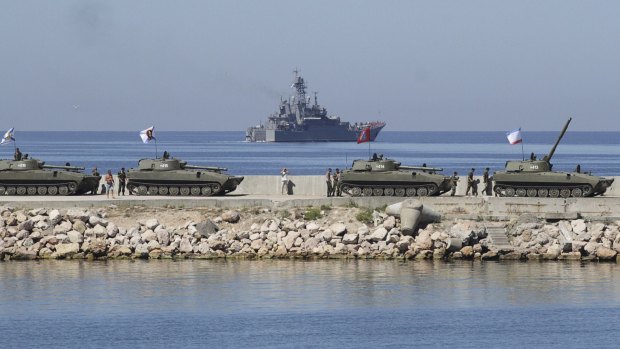 Russian self-propelled howitzers 2S1 Gvozdika, front, and the large landing ship Azov during a rehearsal for the Navy Day parade in Sevastopol.