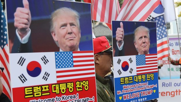 South Koreans hold banners during a welcoming rally ahead of Donald Trump's visit this week.