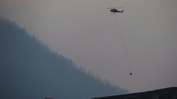 A helicopter battles a bushfire burning on the top of a mountain near Ashcroft, British Columbia, on Monday.