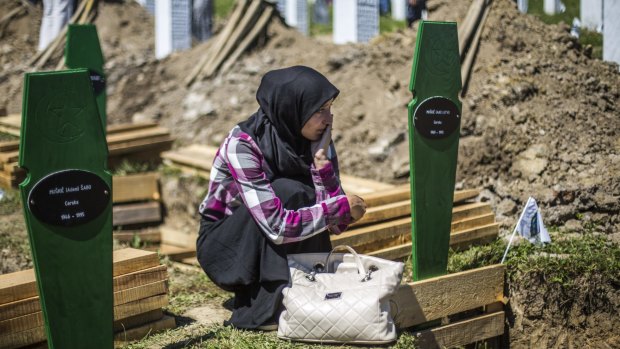 A woman mourns over an open grave before the mass funeral for 136 newly-identified victims of the 1995 Srebrenica massacre. 