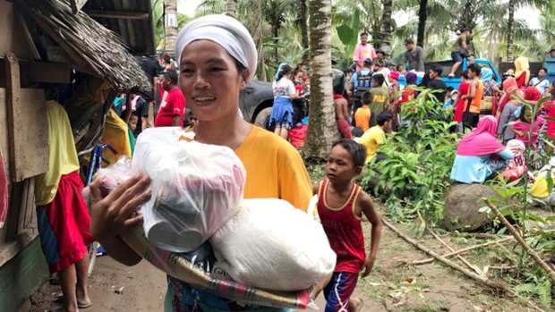 A resident smiles as she walks home with relief supplies being distributed to storm-affected villages of Lanao del Norte in southern Philippines, after Tembin's passing.