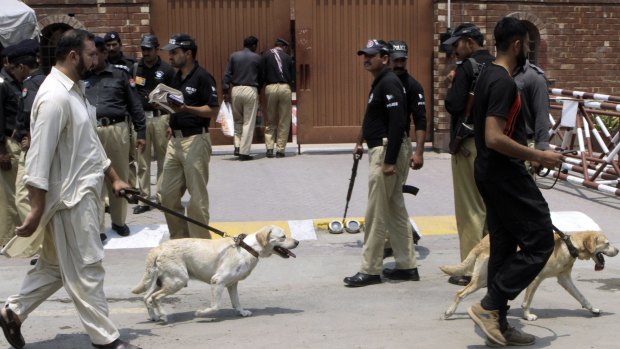 Pakistani security officials use dogs to search the area outside Gaddafi Stadium.