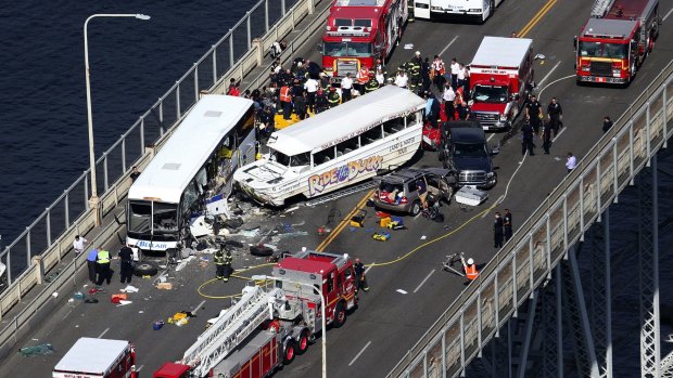 Emergency personnel work at the scene of a fatal collision involving a charter bus, centre left, and a Ride the Ducks amphibious tour bus.