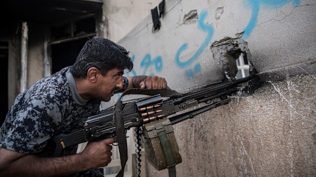 An Iraqi policeman fires a machine gun at an Islamic State position during the battle to recapture west Mosul.