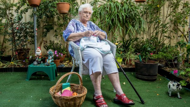 Margaret McClune, 85, knits in the backyard of her assisted living home by the fence that will be just metres from a new pub development next door in Casula, Sydney.