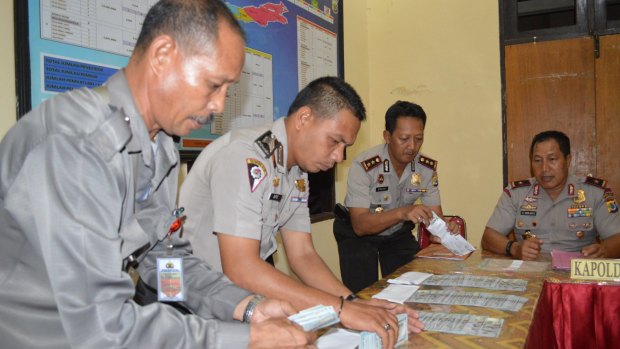 Police officers displaying six stacks of $US100 bills during a press conference by Nusa Tenggara Timur police chief Endang Sunjaya at Rote police station in June.