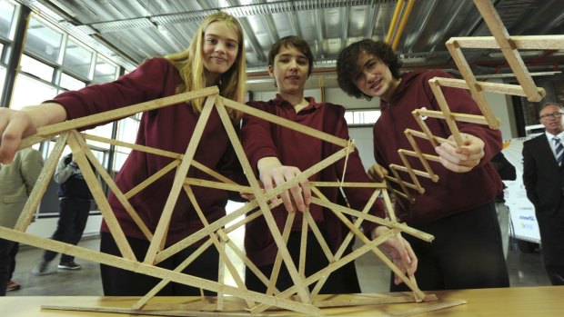 Namadgi School year 8 students Brianna Cather, Kiran Watkins-Molan and Shaun Payne with the remains of their 560-gram bridge, which took 112 kilograms of weight before snapping.