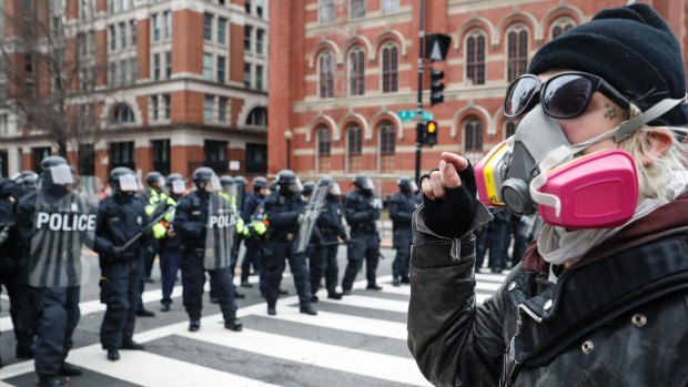 A protester faces off with a line of riot police after the inauguration.