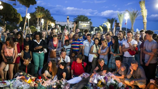 People gather at a makeshift memorial to honor the victims of an attack, near the area where a truck mowed through revelers in Nice. 