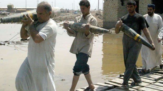 Iraqis clear away unexploded ordnance left behind by retreating Iraqi troops in a residential area of Baghdad in 2003.