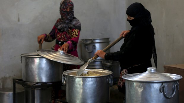 Syrian displaced women prepare food to be distributed for the displaced people at a refugee camp, in Ain Issa town, north-east Syria in 2017.