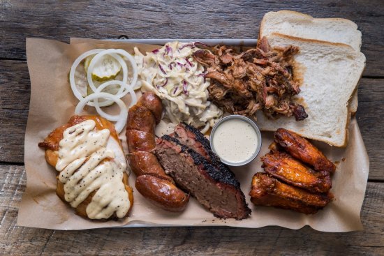 "Pitmaster selection" platter (clockwise from top right) pulled pork, buffalo hot chicken wings, brisket, house-made sausage, smoked chicken breast with Alabama-style white sauce, pickles and coleslaw.