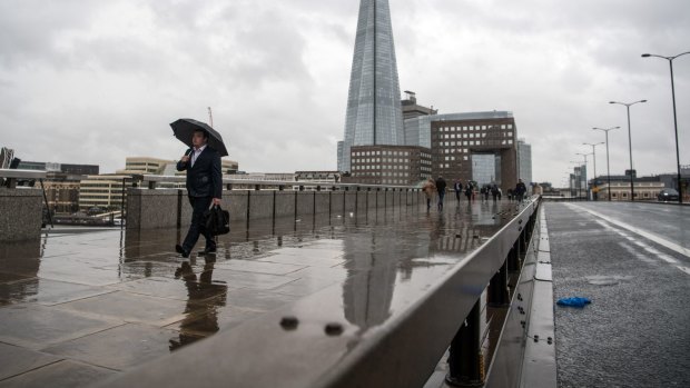 Pedestrians walk alongside a security barrier erected to stop vehicles mounting the footpath on London Bridge.